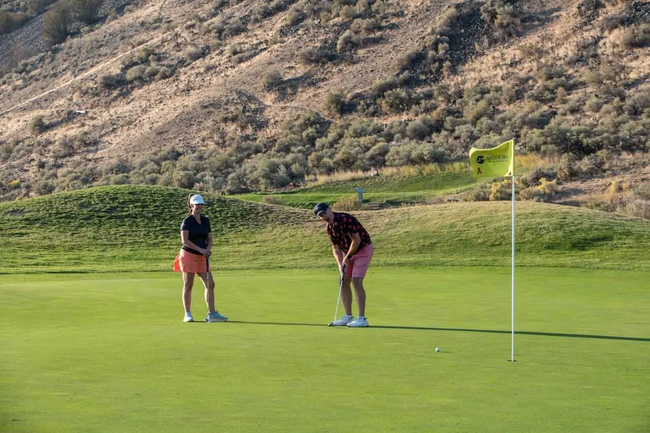 Golfer putting on a scenic green with Kamloops hillside views at Bighorn Golf.