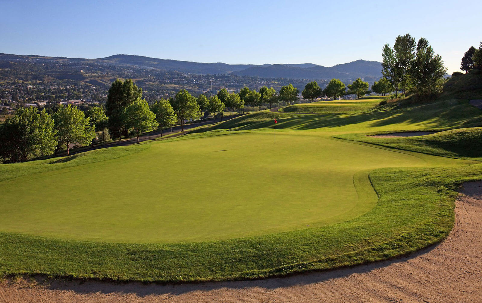 Scenic green at Bighorn Golf Course overlooking Kamloops valley with rolling fairways and tree-lined hills