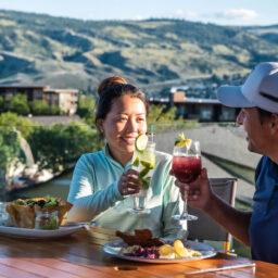 Couple enjoying drinks and dining on a scenic patio overlooking Kamloops valley and golf course