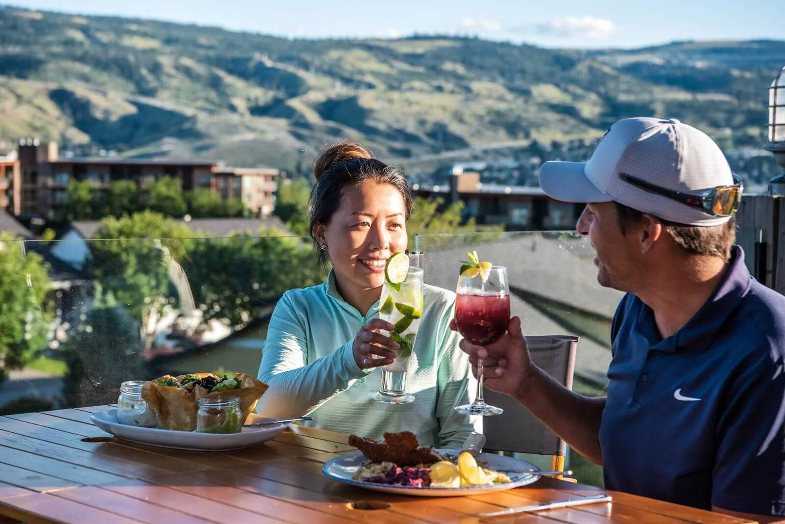 Couple enjoying drinks and dining on a scenic patio overlooking Kamloops valley and golf course