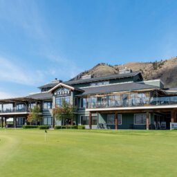 Modern golf clubhouse with patio dining overlooking green and Kamloops hillside landscape