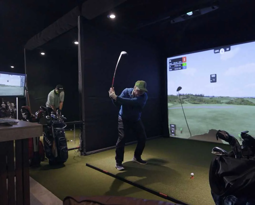 Golfer practicing his swing at a premium indoor golf simulator at Bighorn in Kamloops.