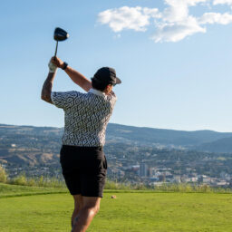 Gemini said Golfer teeing off from an elevated tee box with panoramic views of Kamloops.