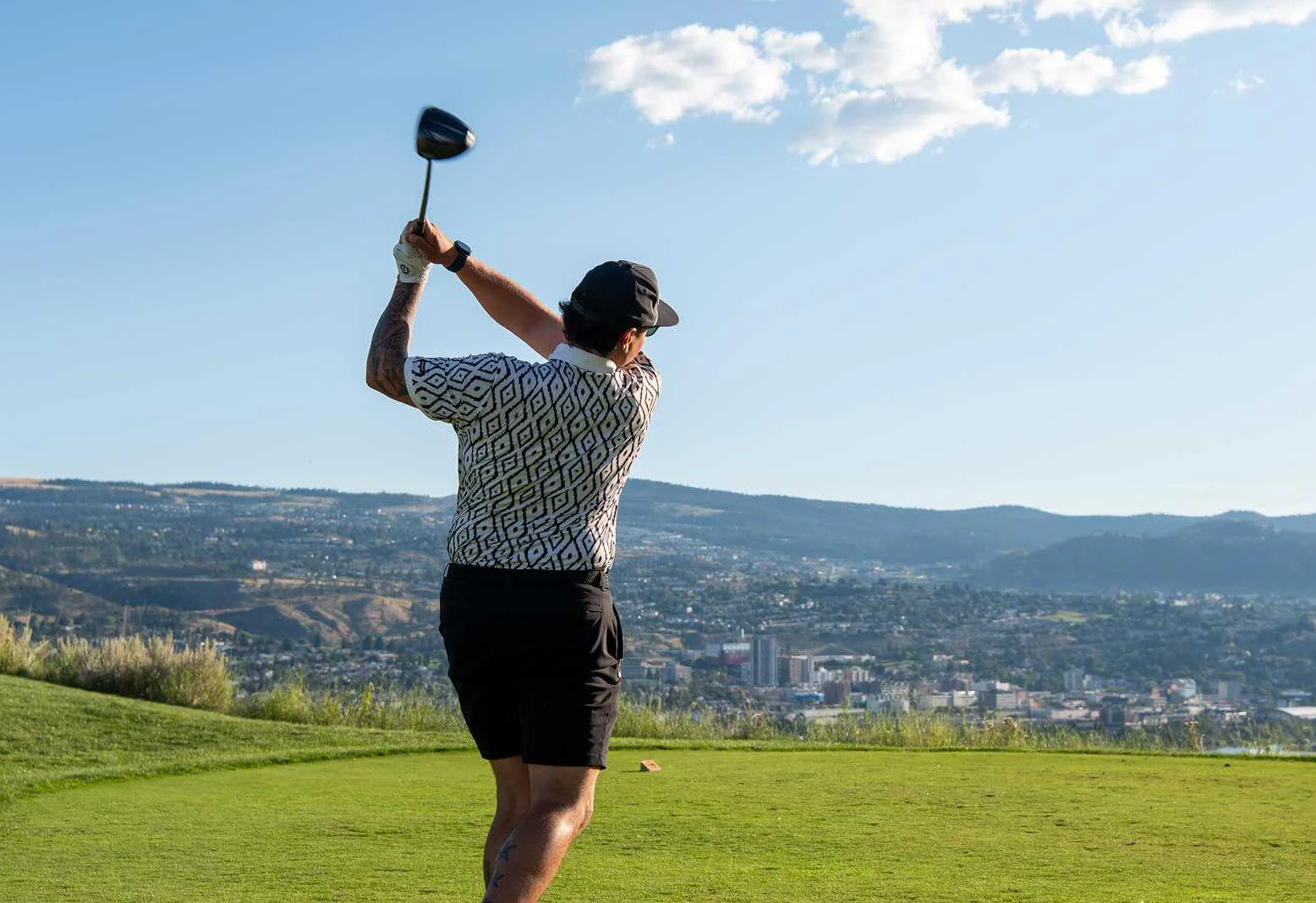 Gemini said Golfer teeing off from an elevated tee box with panoramic views of Kamloops.