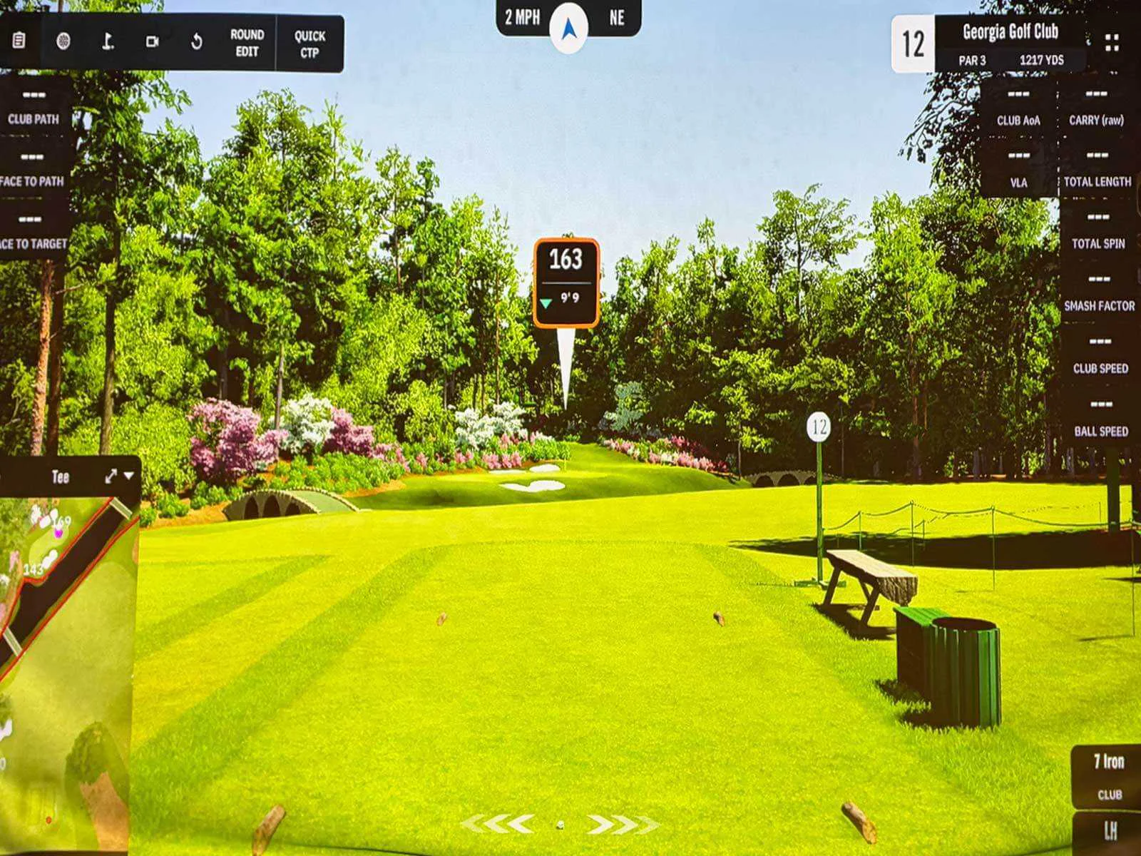 Gemini said An aerial view of two golfers walking across a sunlit green toward a yellow flag, with deep shadows stretching across the grass and a large sand bunker visible in the lower foreground.