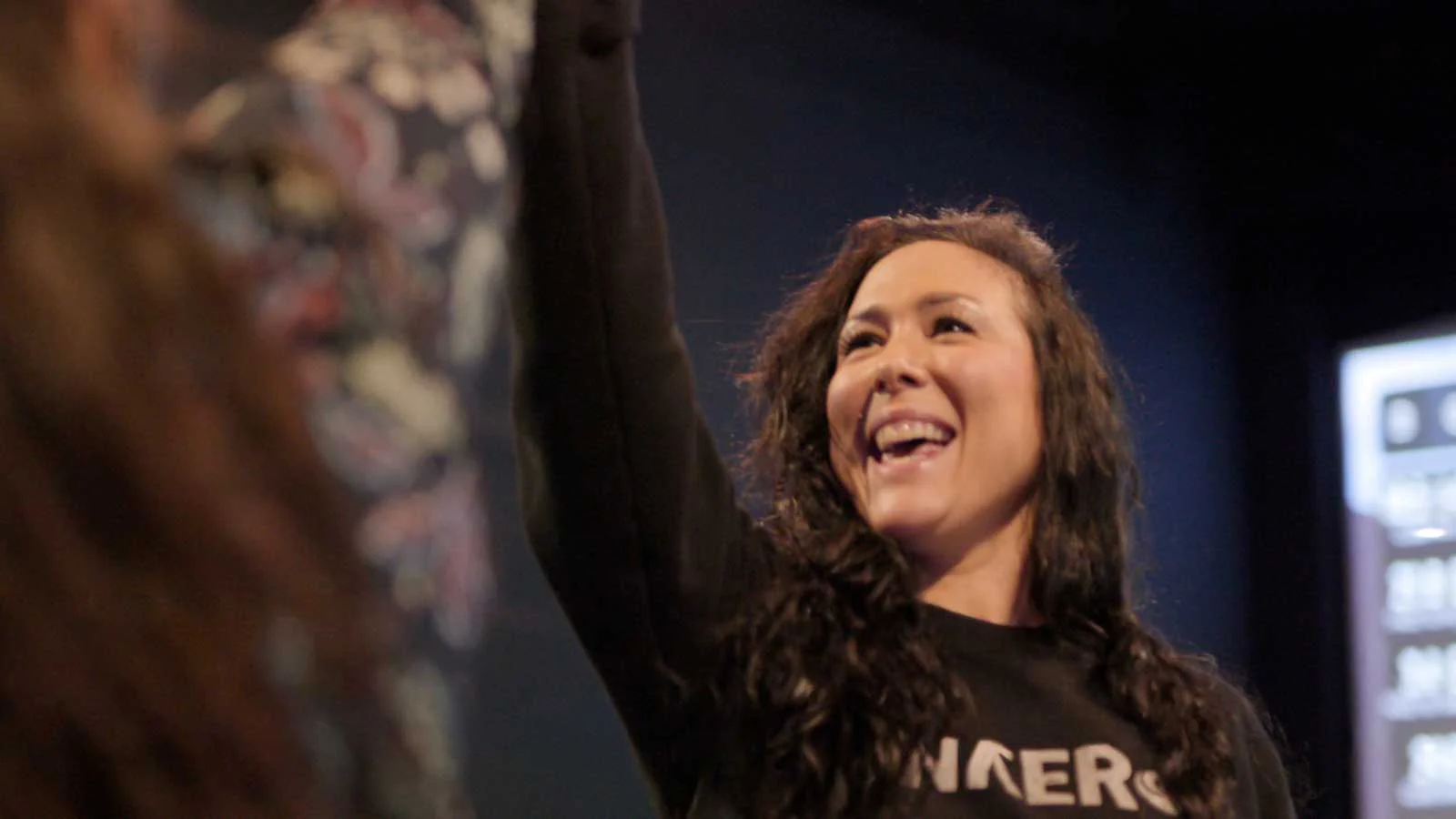 Woman smiling and raising hand in high-five during indoor golf play