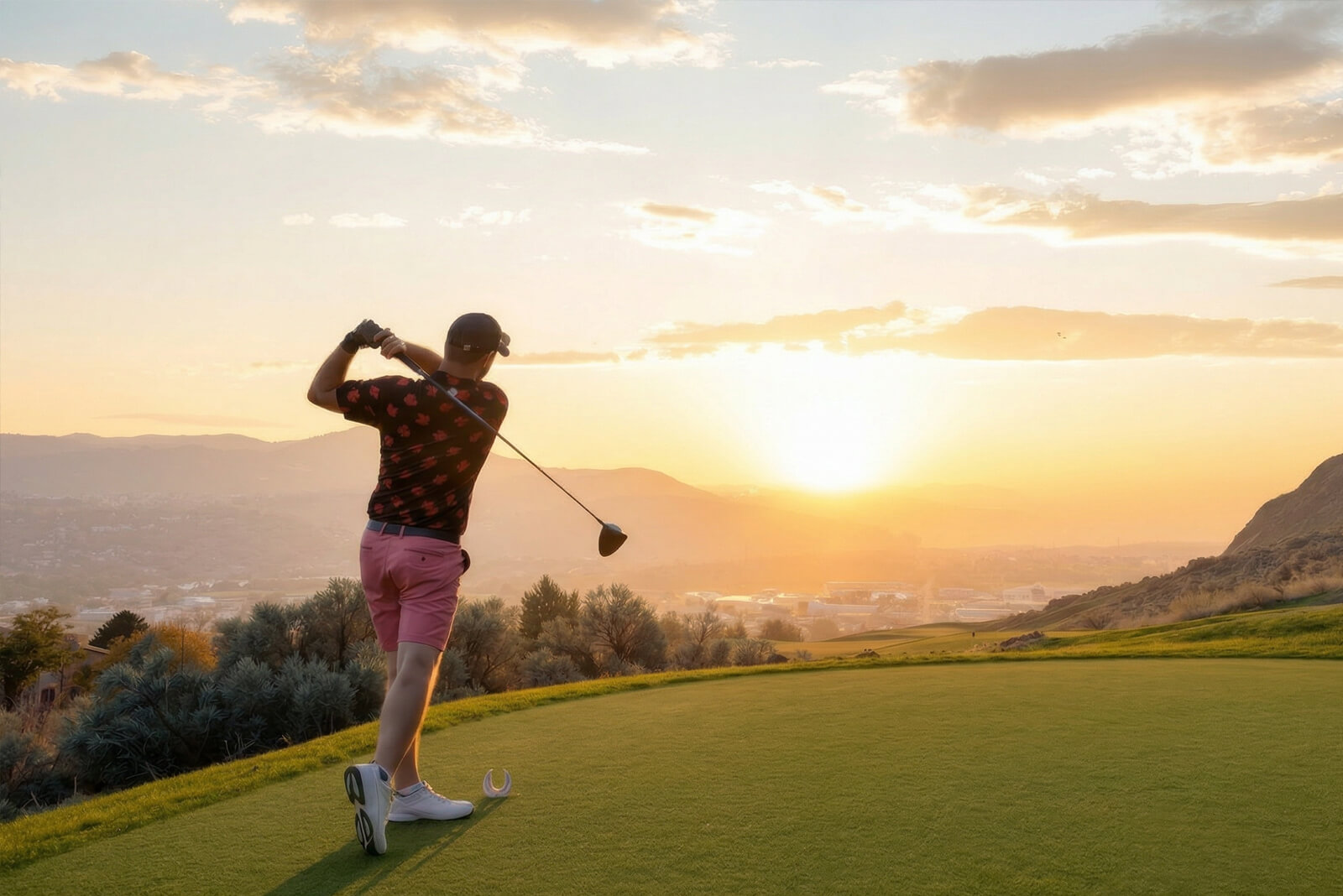 Golfer teeing off at Bighorn Golf Kamloops during sunset with sweeping valley and mountain views