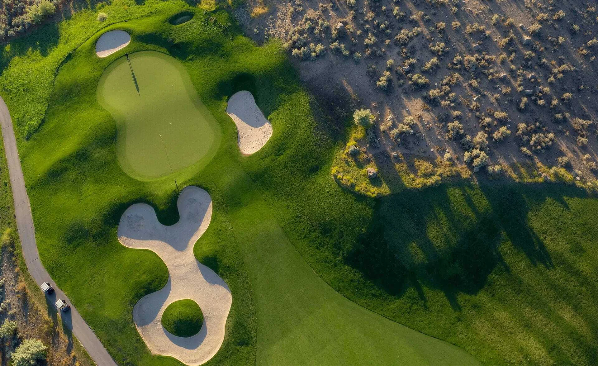 Aerial top-down view of Bighorn Golf Course green with sculpted bunkers, fairway contours, and desert hillside contrast