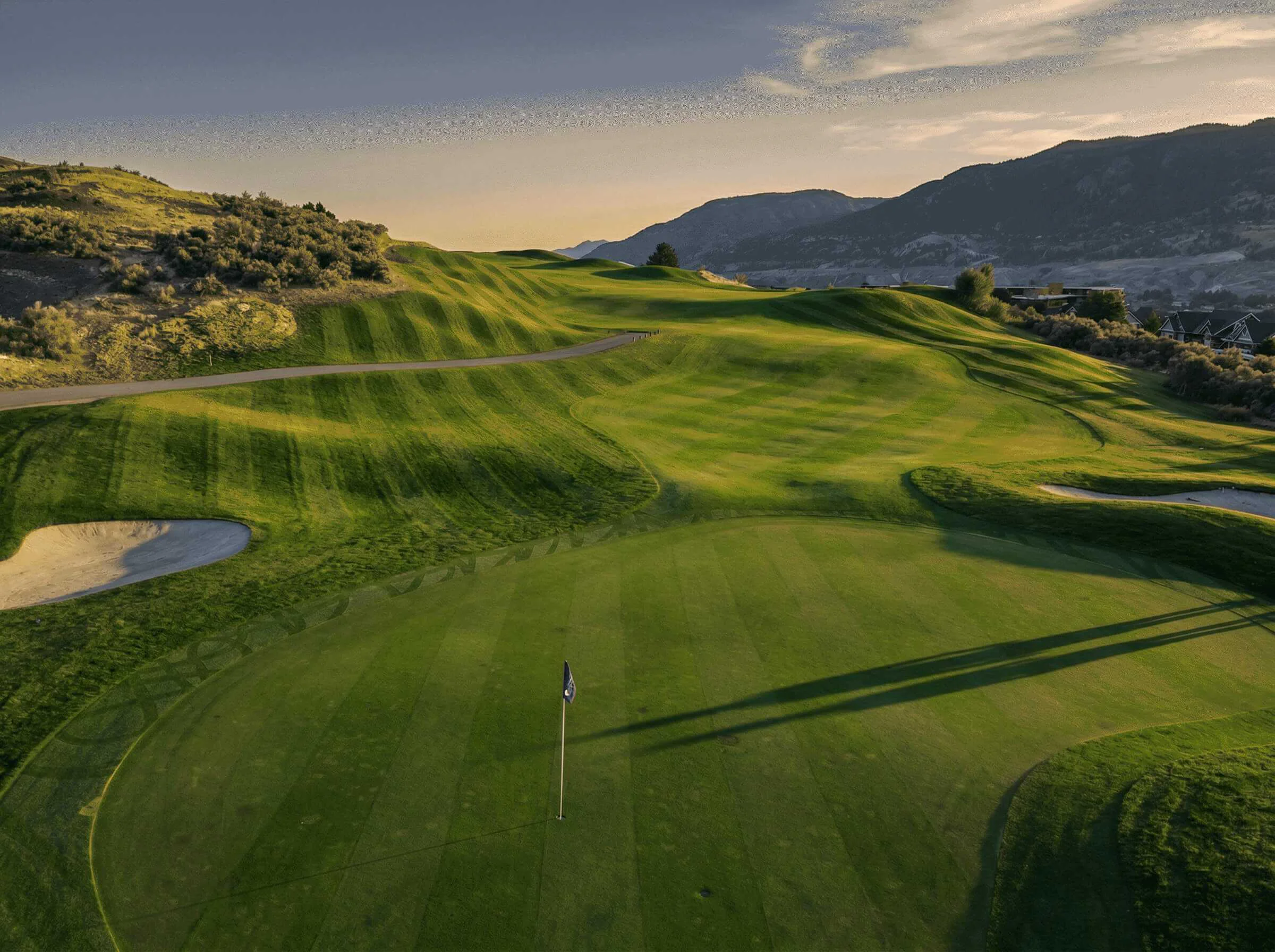 Elevated view of Bighorn Golf Kamloops green and rolling fairway contours with long evening shadows