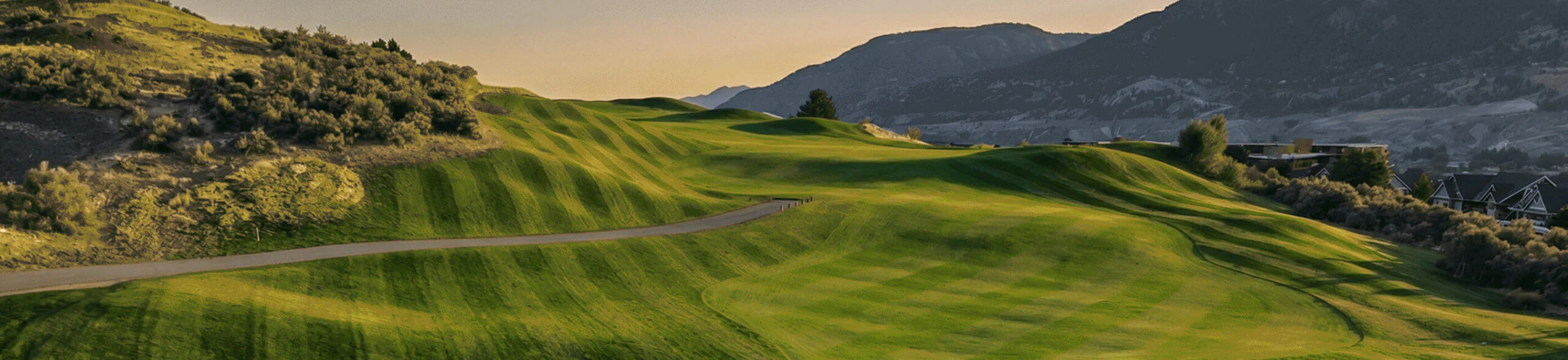 Rolling fairway contours at Bighorn Golf Kamloops with cart path weaving through sunlit hillside terrain