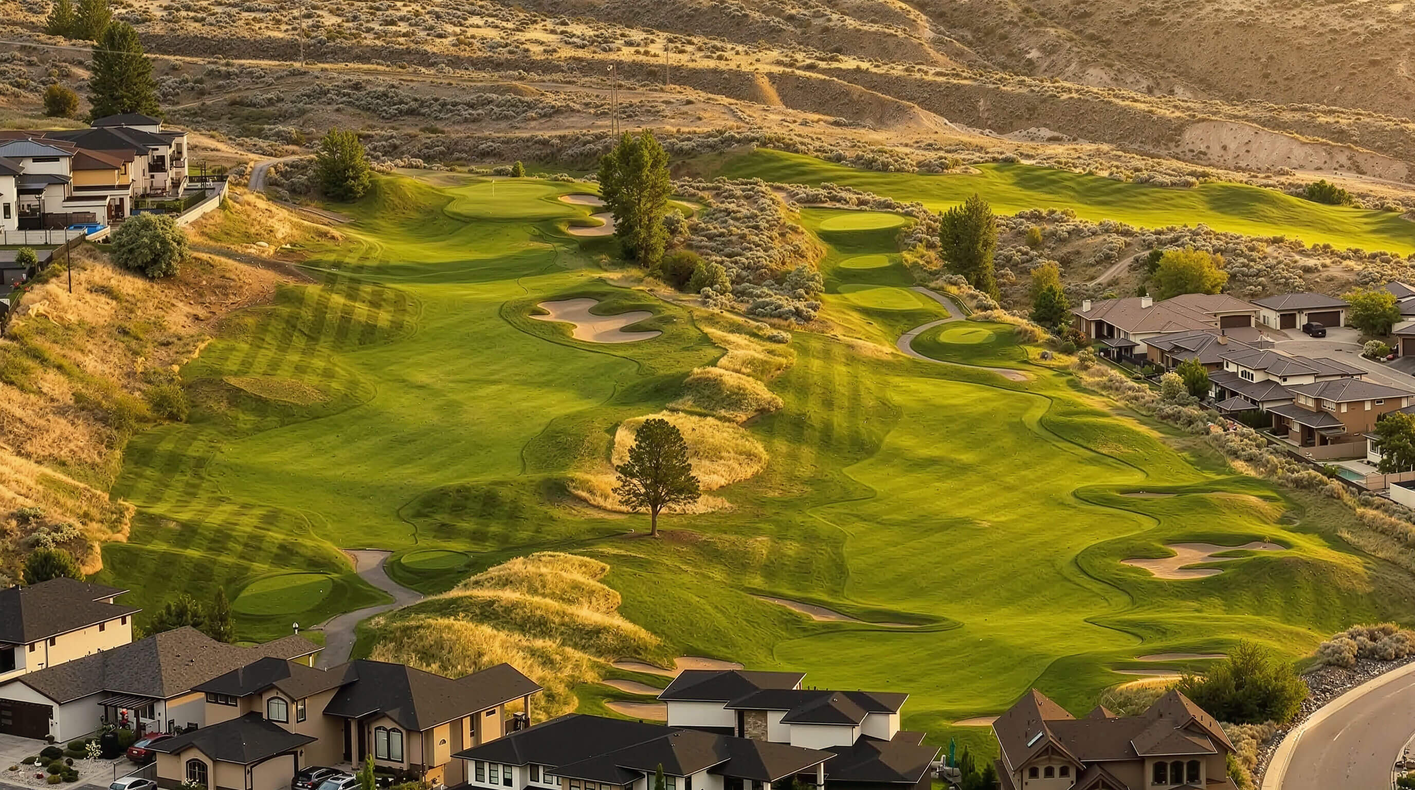 Elevated view of Bighorn Golf course in Kamloops with rolling fairways, bunkers, and surrounding hillside homes