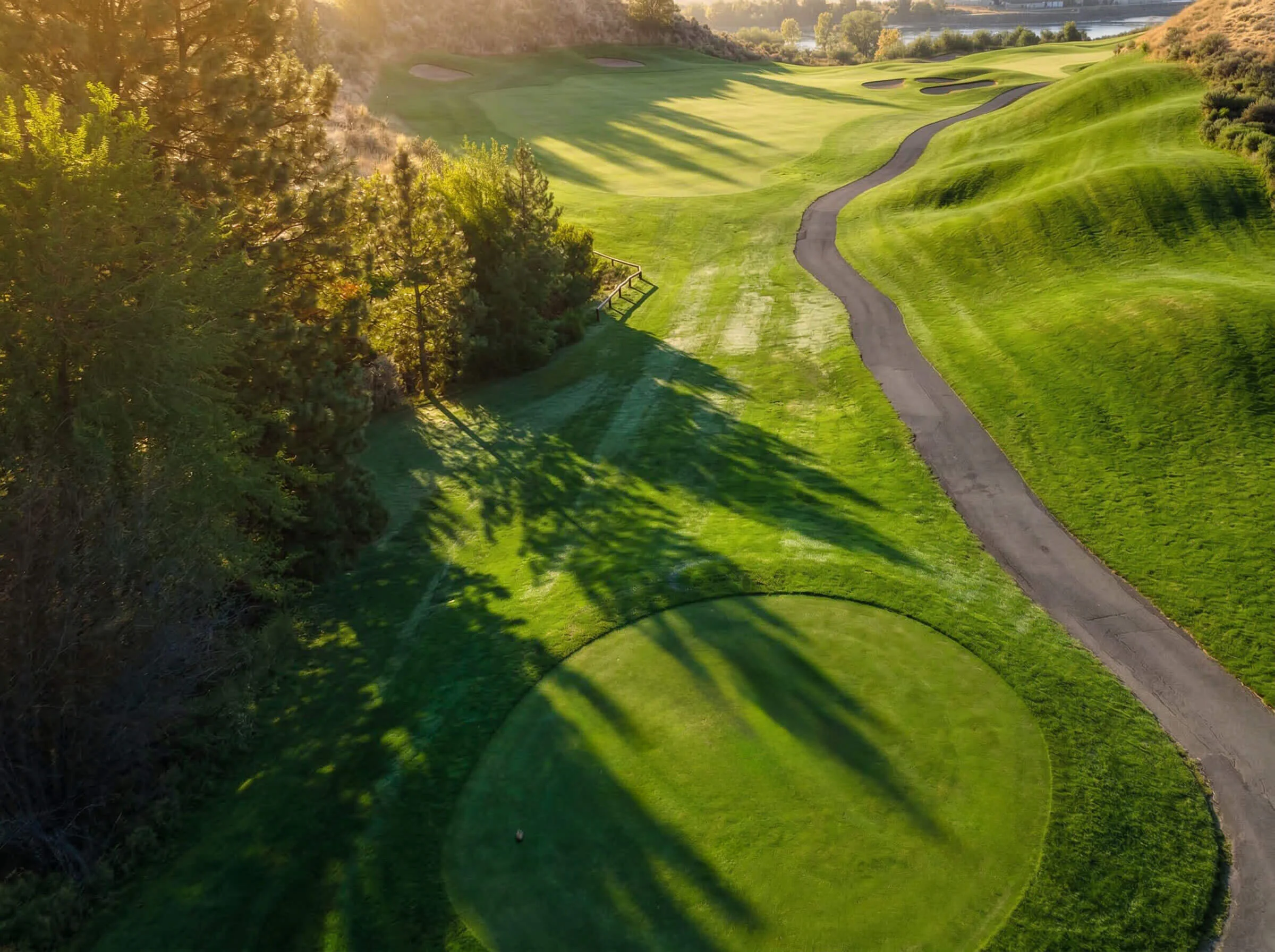 Tee box overlooking rolling fairway and cart path at Bighorn Golf Kamloops during golden hour